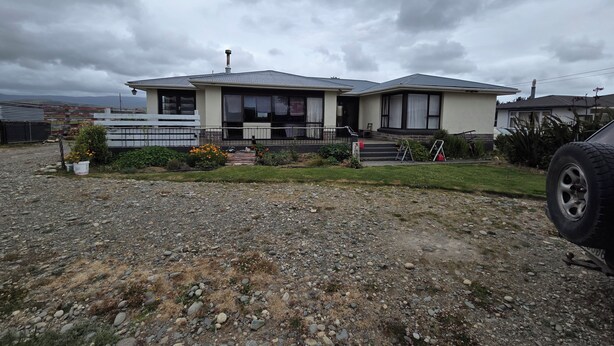 A two-story house with a gravel driveway and a parked car.