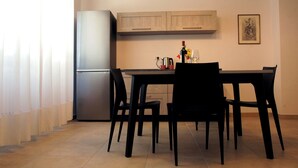 Ein Essbereich mit Tisch, Stühlen, einem Kühlschrank und einem an der Wand befestigten Schrank.
