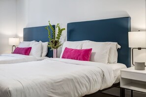 A hotel room with two beds, white bedding, and a blue headboard. - Gateway Suites: Cozy Getaway Near Banff/Canmore (Harvie Heights)