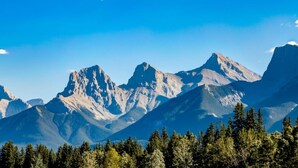Une chaîne de montagnes avec un ciel dégagé et une forêt dense à ses pieds.