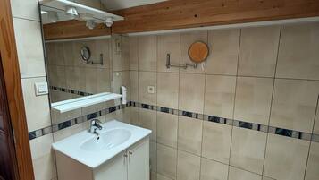 A modern bathroom with a skylight, a sink with a mirror, and a wooden beam ceiling.