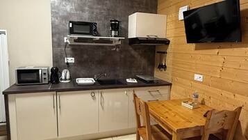A compact kitchen with a microwave, coffee maker, and a TV mounted on the wall.
