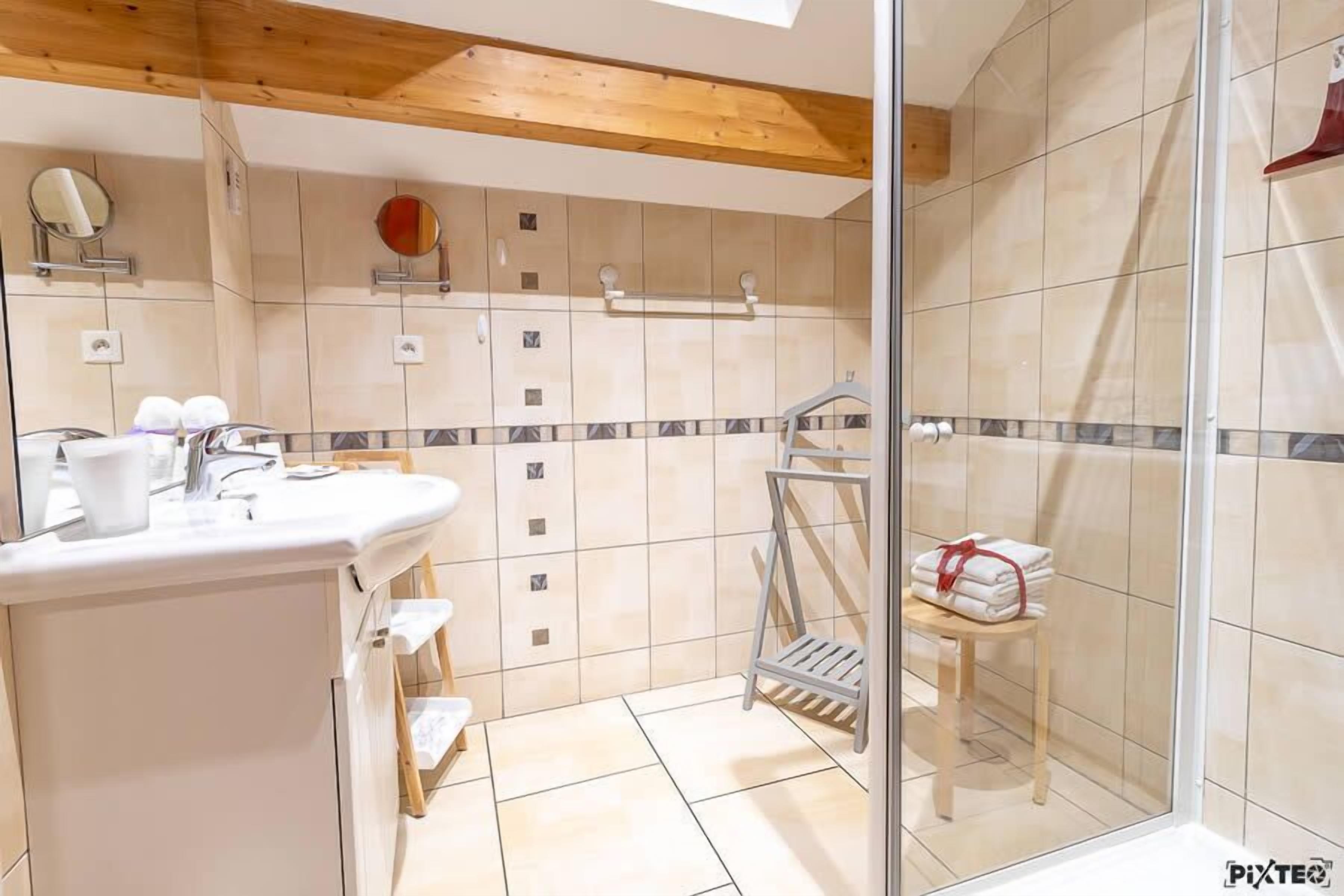 A bathroom with a sink, mirror, and tiled walls.