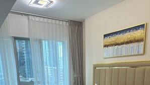 Een hotelkamer met een groot bed, houten vloer, stadszicht door het raam en een schilderij aan de muur.