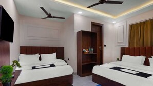 A hotel room with two beds, ceiling fans, a TV, a wardrobe, and a small plant. - SG Royal Portico (Haridwar)