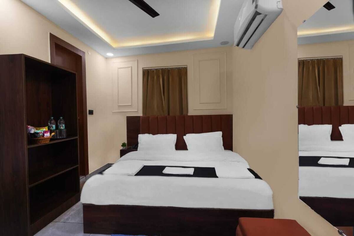 A hotel room with a large bed, a wooden wardrobe, and a mirror.
