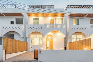 A modern two-story building with a white facade, arched windows, and a wooden fence. - Downtown Oasis Pool Villa Collection – Premium Private Stay Near Walking Street (Nong Prue, Pattaya City)