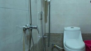 Une petite salle de bain avec une douche, des toilettes et un porte-serviettes.