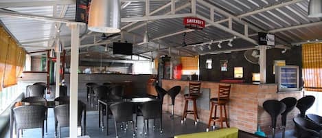 Un restaurante con terraza, zona de bar y cocina a la vista.