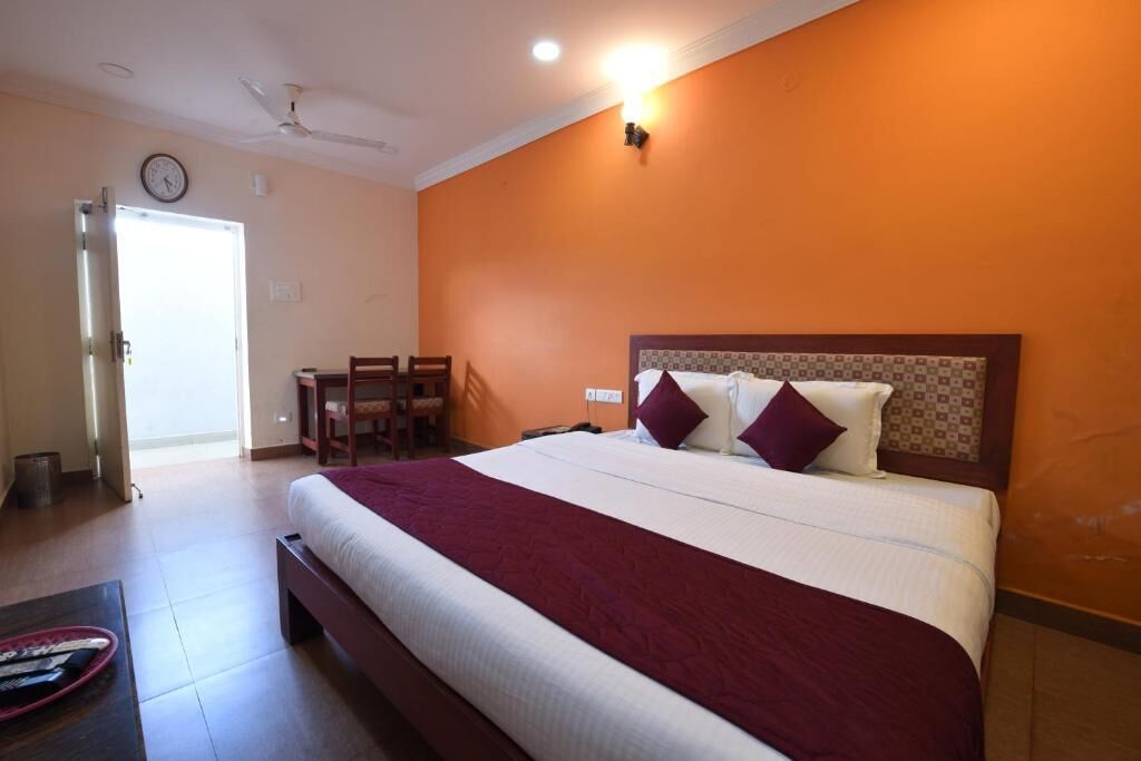 A hotel room with a large bed, a desk, and a chair.