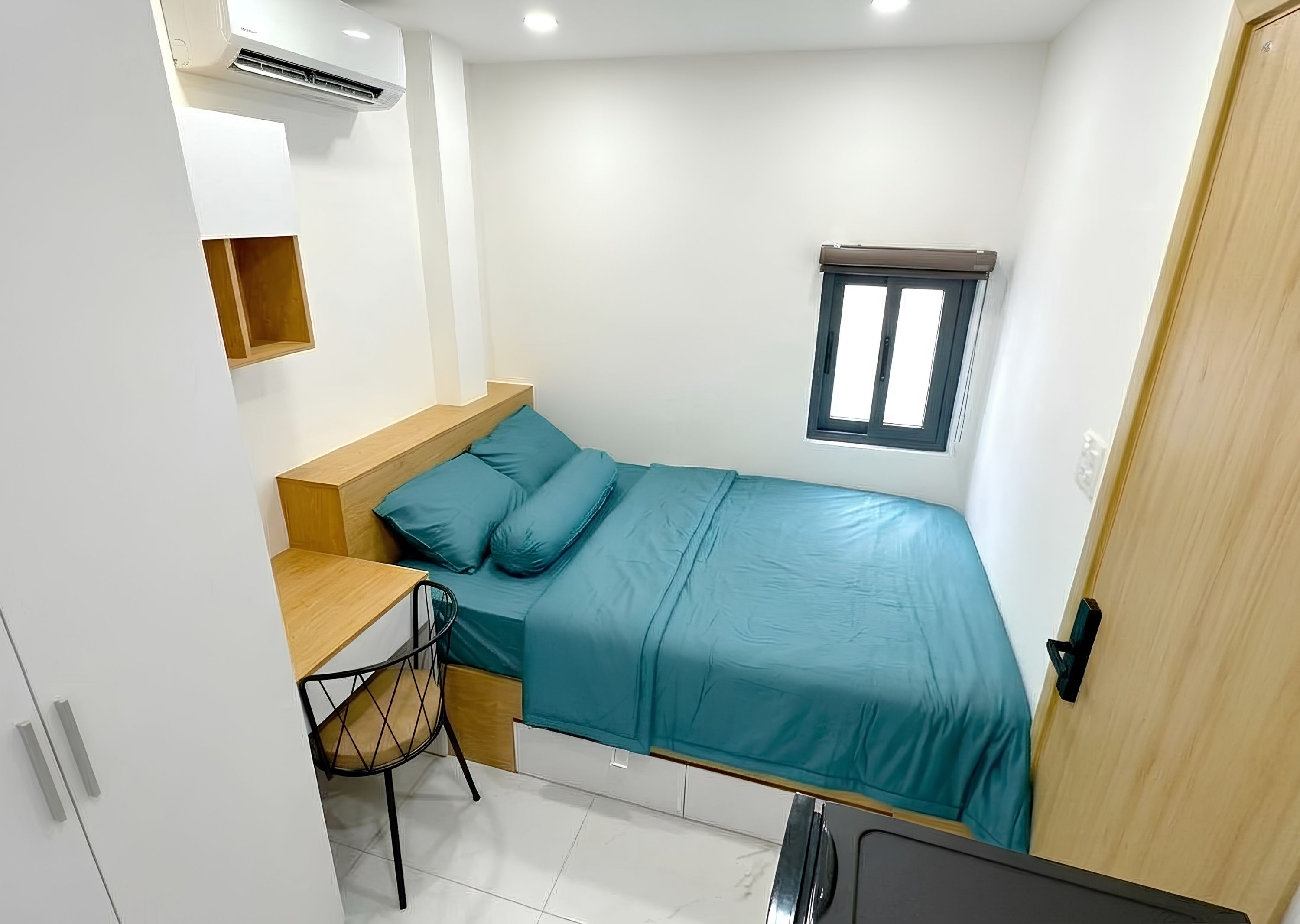A compact bedroom with a bed, a desk, and a chair.