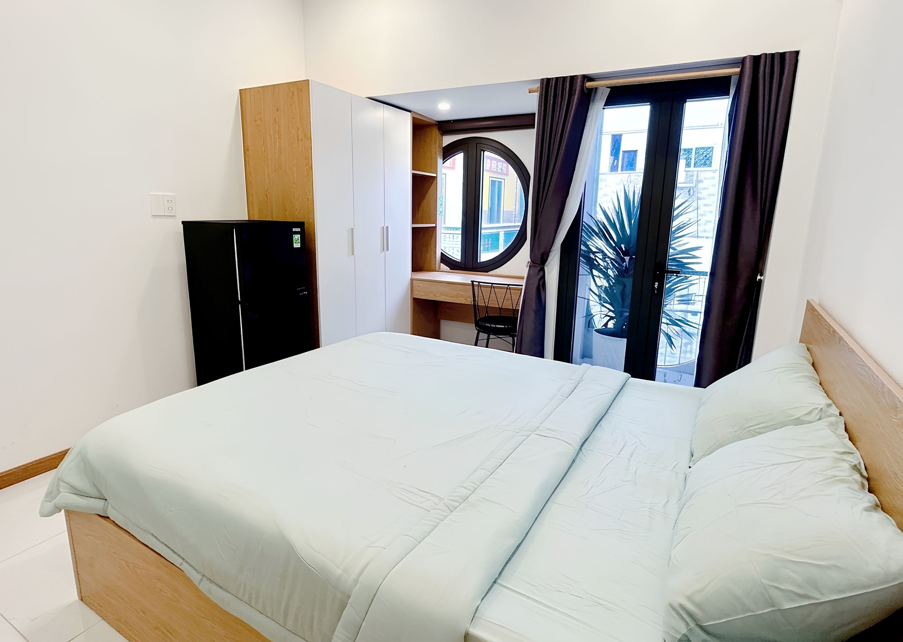 Ein Hotelzimmer mit Bett, Schreibtisch, Kleiderschrank und Blick nach außen.