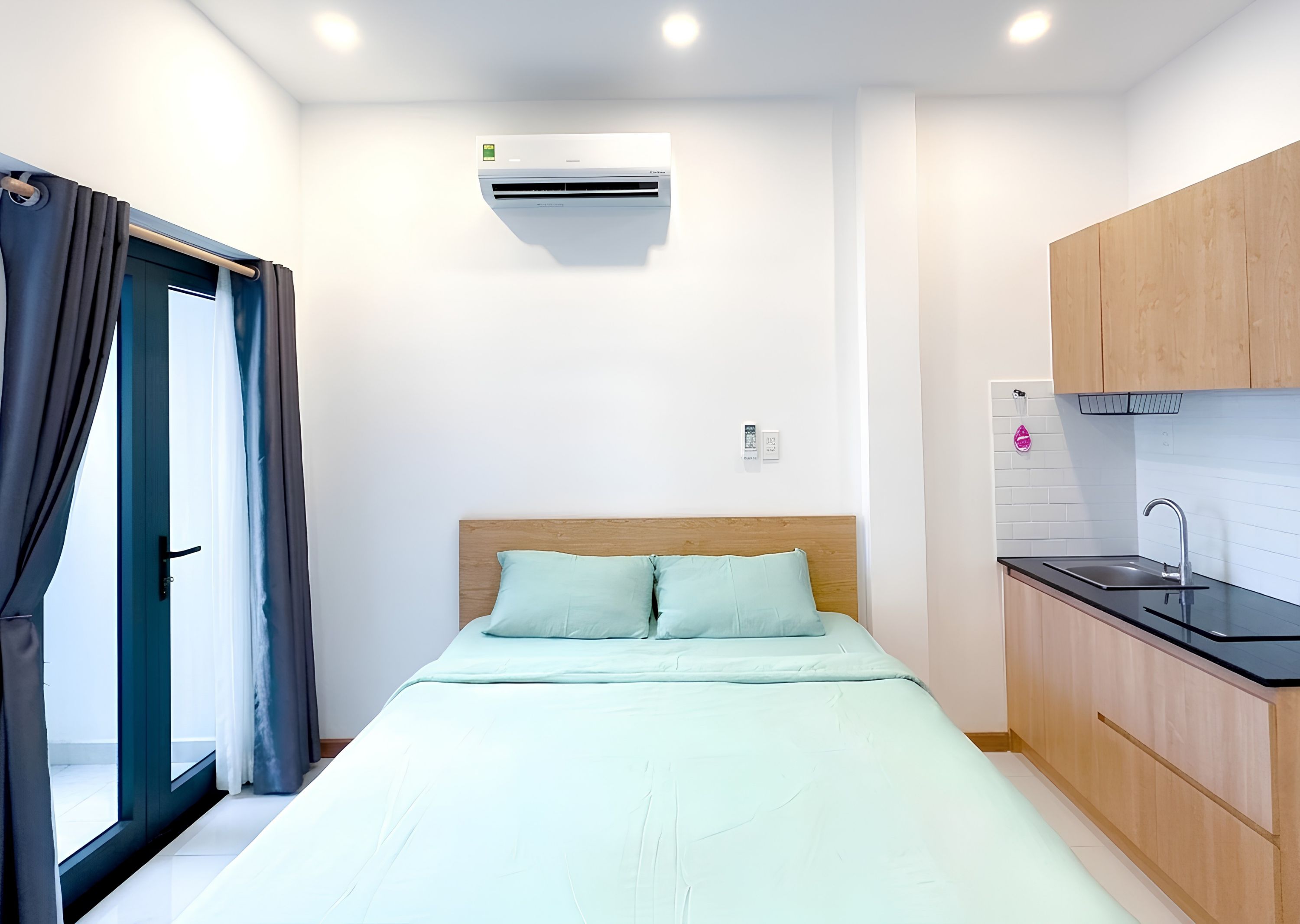Quarto compacto com cama, cozinha compacta e ar-condicionado.