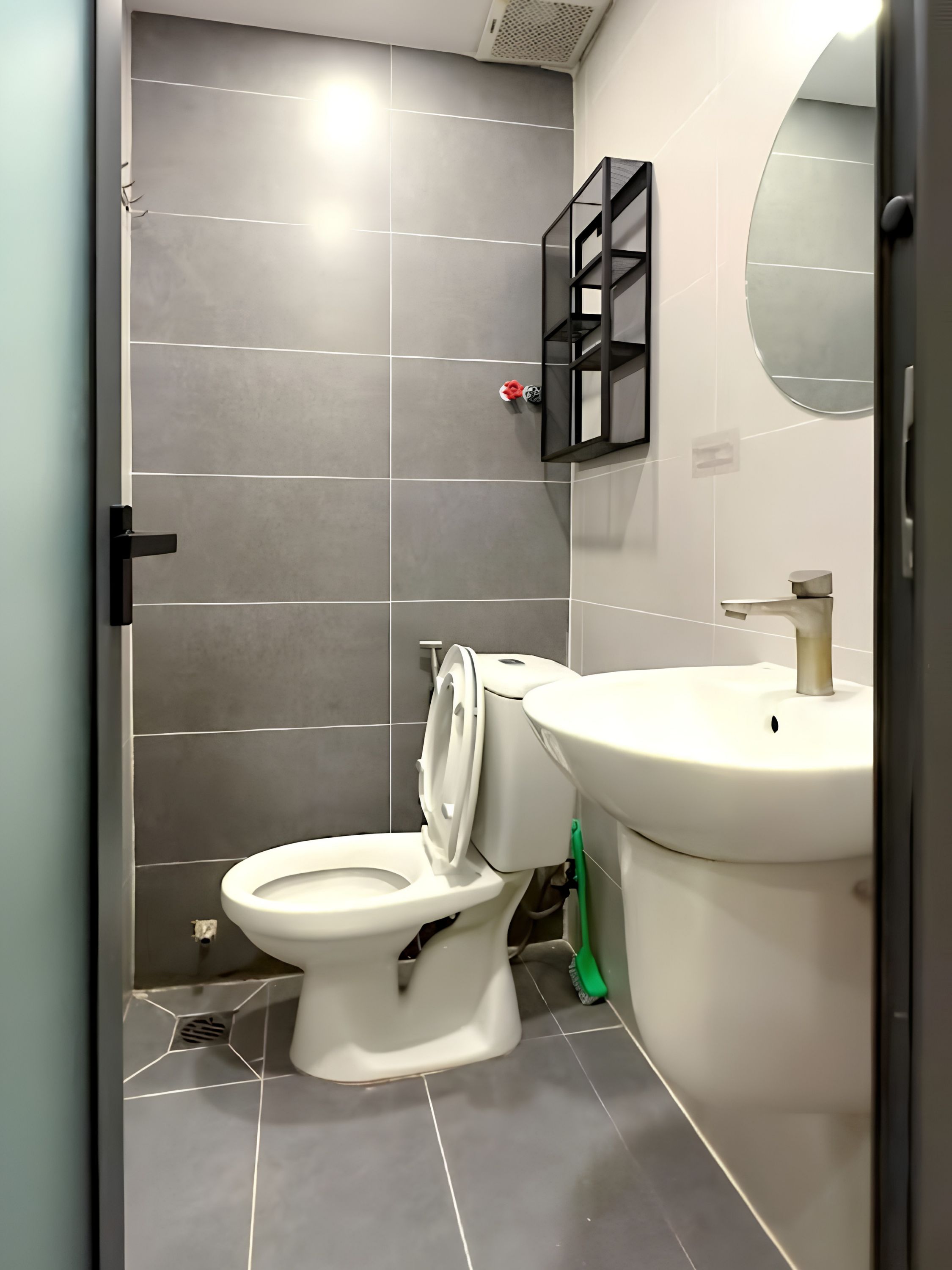 A bathroom with a toilet, sink, and mirror.