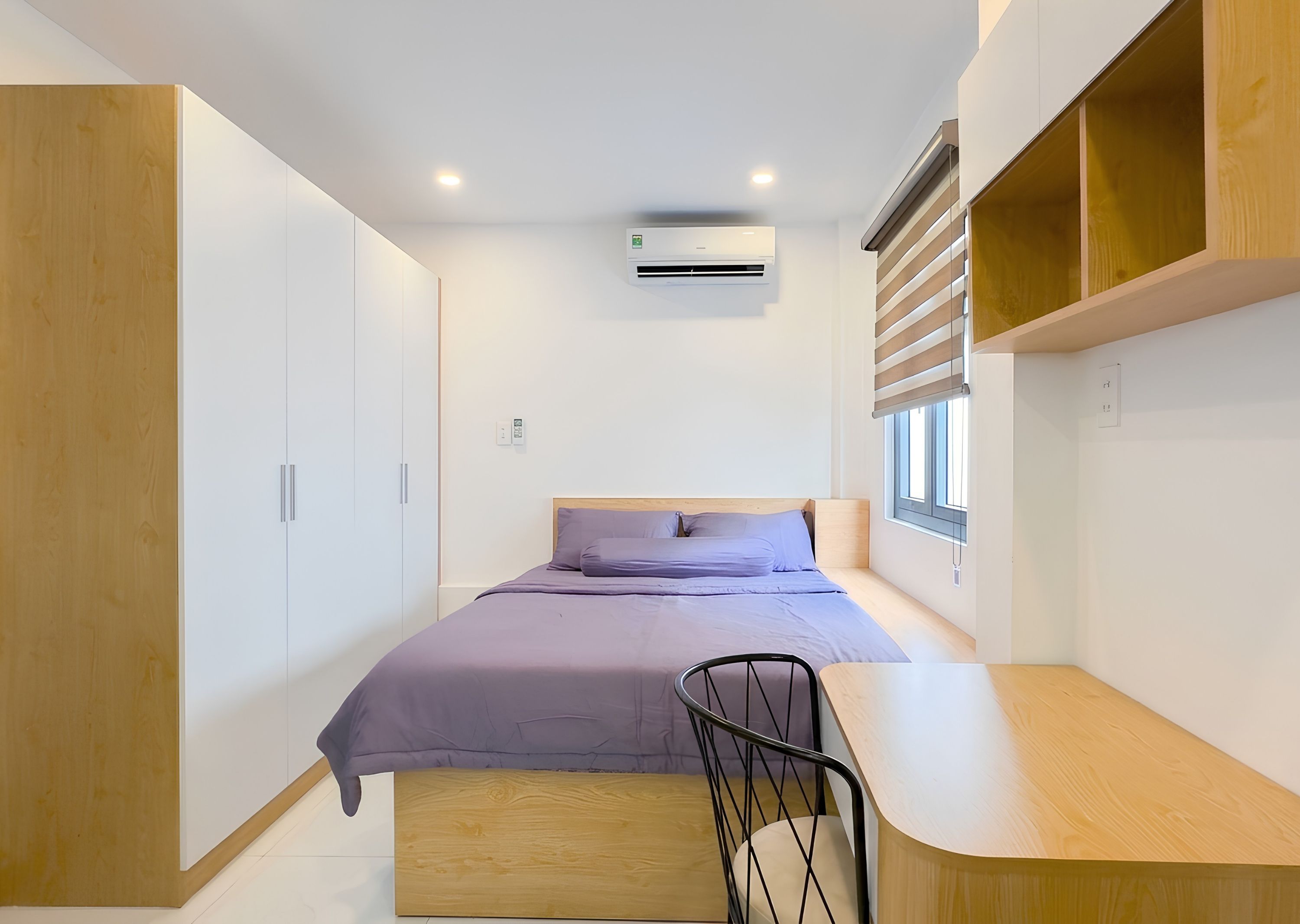A bedroom with a bed, a desk, and a chair.