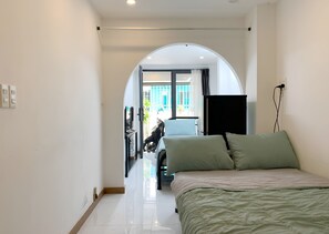 A bedroom with a bed, a TV, and a view through an arched doorway to an outdoor area with a scooter. - Lunaria Maison - Saigon Local, District 3 (Ho Chi Minh City)