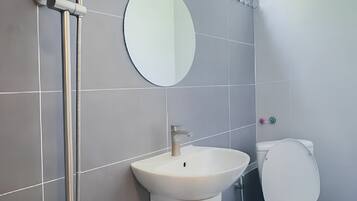 Et moderne badeværelse med bruser, håndvask og toilet.
