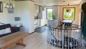 Un vaste espace de vie comprenant un banc en bois, une table à manger et une cuisine située à l’arrière-plan.