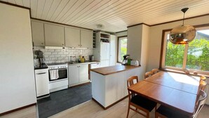 Une cuisine moderne avec des meubles blancs, une table à manger en bois et une grande fenêtre.