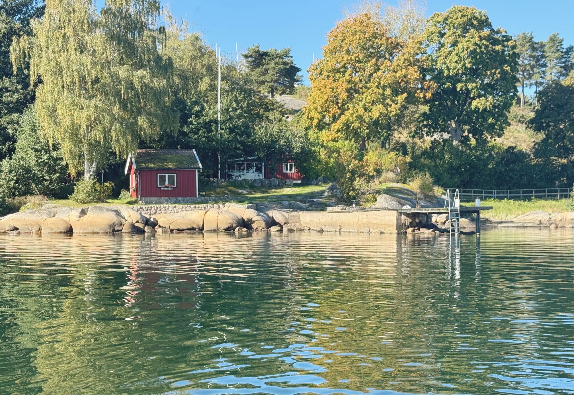 Une scène paisible au bord d’un lac, avec un chalet rouge et une jetée qui s’avance dans l’eau.