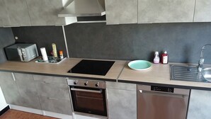 A modern kitchen with a built-in oven, dishwasher, and a black stovetop.