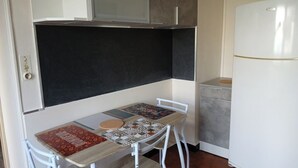 A compact kitchenette with a small table, a refrigerator, and a cabinet.