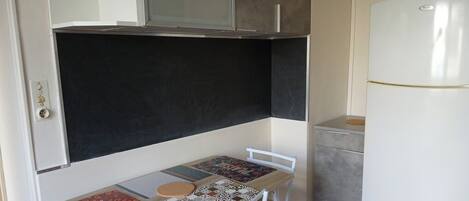 Une petite cuisine équipée comprenant une table, un réfrigérateur et un placard.