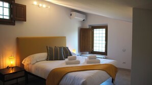A bedroom with a bed, bedside lamp, air conditioning unit, and a window. - Michelangelo Apartment (Toscana)