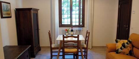 A dining area with a table, chairs, a cabinet, and a sofa.