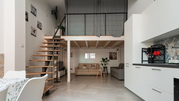 A modern interior with a staircase, a sofa, a dining table, and kitchen cabinets. - GuestHost - A comfortable and welcoming 56 square meters studio apartment, perfect for five people, located on the ground floor of a building with a private entrance.The property is located in the Affori neighborhood, an area full of amenities, including (Milan)