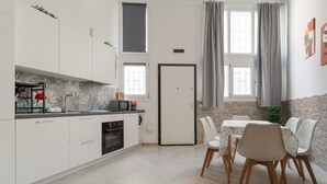 A modern kitchen with white cabinets, a built-in oven, and a dining area with a table and chairs. - GuestHost - A comfortable and welcoming 56 square meters studio apartment, perfect for five people, located on the ground floor of a building with a private entrance.The property is located in the Affori neighborhood, an area full of amenities, including (Milan)