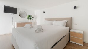 A modern hotel room with a large bed, a bedside table, a flat-screen TV mounted on the wall, and a small potted plant. - GuestHost - A comfortable and welcoming 56 square meters studio apartment, perfect for five people, located on the ground floor of a building with a private entrance.The property is located in the Affori neighborhood, an area full of amenities, including (Milan)