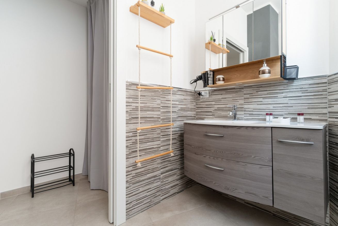 Une salle de bain moderne avec un meuble-lavabo en bois, un miroir et un porte-serviettes mural.