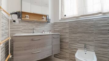 Ein modernes Badezimmer mit einem Holzwaschtisch, einem Bidet und einem Spiegel über dem Waschtisch.