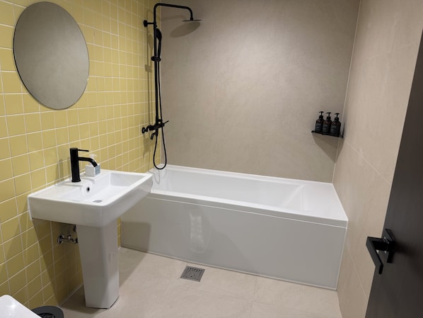 A bathroom with a white sink, a bathtub, a shower, and a mirror.