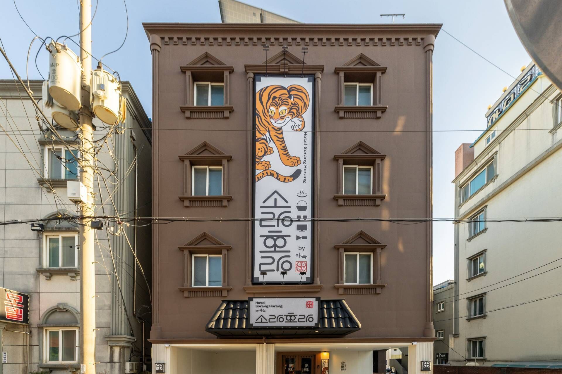 A building with a large tiger mural on the facade, multiple windows, and a sign indicating it is Hotel Sorang Horang.