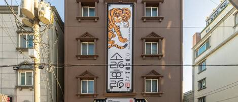 A building with a large tiger mural on the facade, multiple windows, and a sign indicating it is Hotel Sorang Horang.