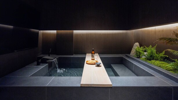 A modern spa area with a central hot tub, a wooden bench, and a bottle of water. - Gangneung Sorang Horang Hotel by Anook (Gangneung)