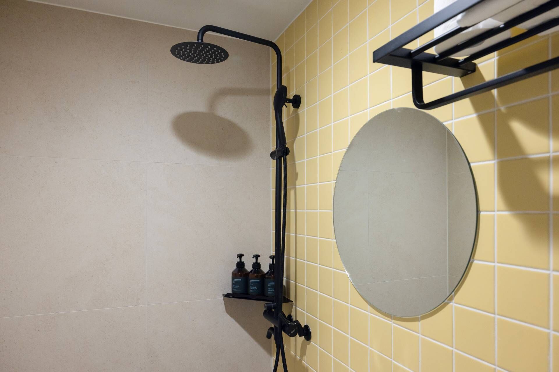 A bathroom with a shower, a towel rack, and a mirror.