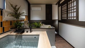 A modern bathroom with a built-in hot tub, a stone feature, and a traditional Japanese-style window. - Gangneung Sorang Horang Hotel by Anook (Gangneung)
