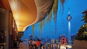 An outdoor seating area with a view of a city skyline and a tower. - Ceylonz Suites by Mana Mana (Kuala Lumpur)
