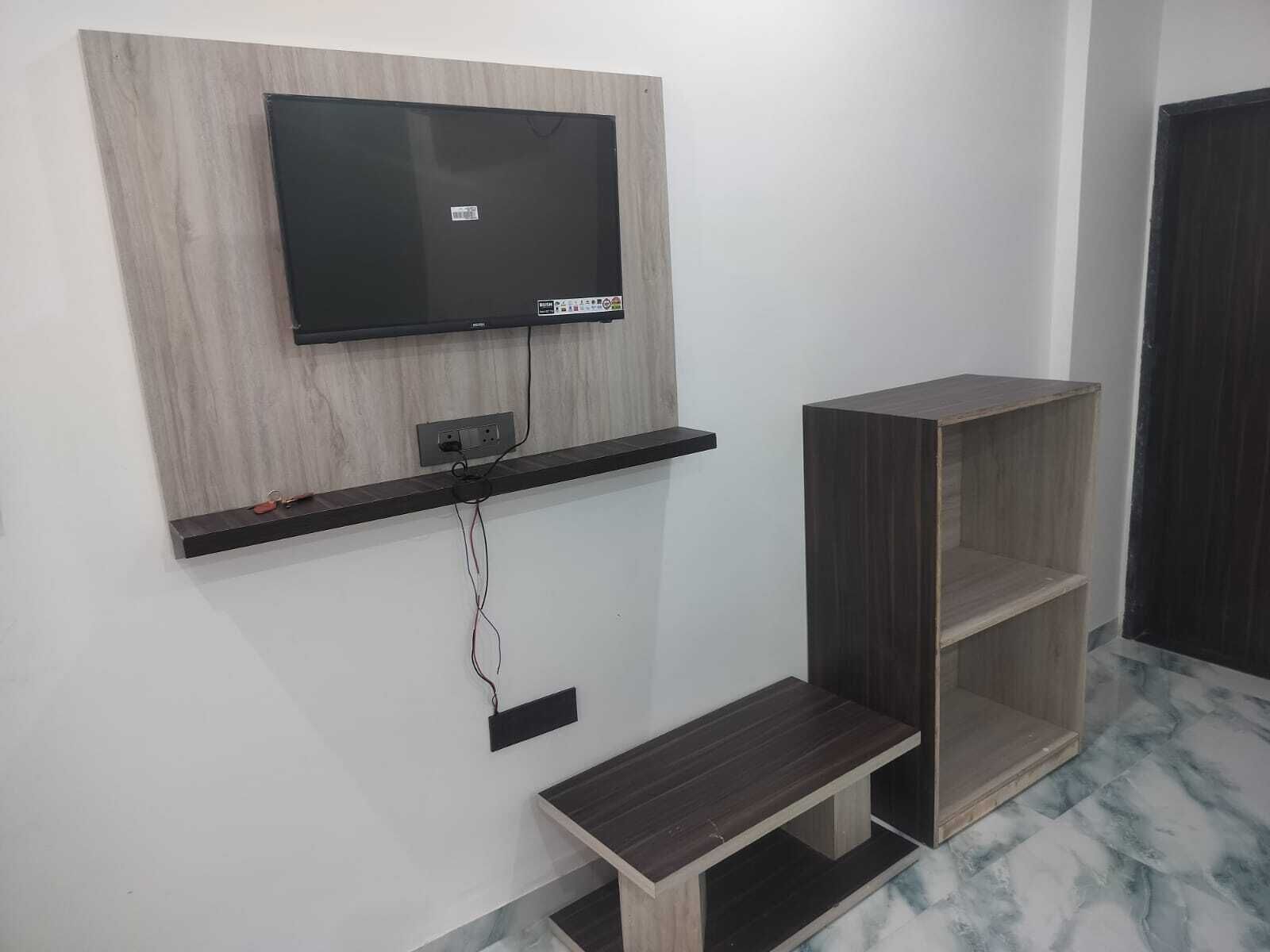 A modern living room with a mounted TV, a wooden shelf, and a built-in bench.