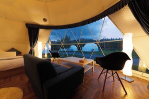 Habitación tipo cabaña con cama, mesa, dos sillas y vistas al exterior.