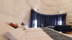 A spacious room with a large bed, a desk, and a chair, featuring a curved ceiling and a view of the outdoors. - Gramping Stay Tomamu (Shimukappu)