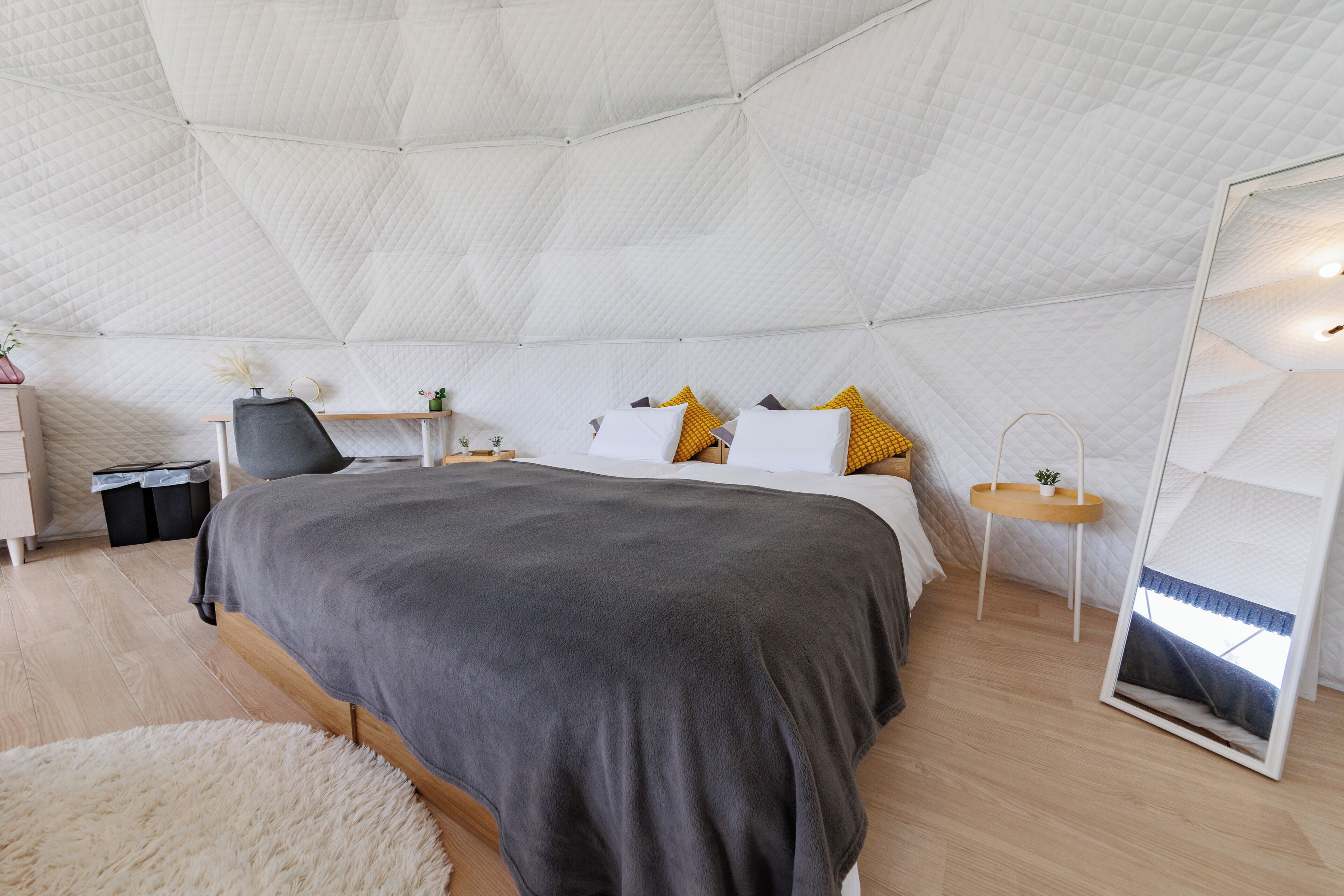 A bedroom with a large bed, bedside tables, a mirror, and a fluffy rug.