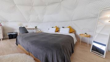 A bedroom with a large bed, bedside tables, a mirror, and a fluffy rug.