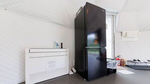 A kitchenette with a black refrigerator, a white microwave, and a small countertop. - Gramping Stay Tomamu (Shimukappu)