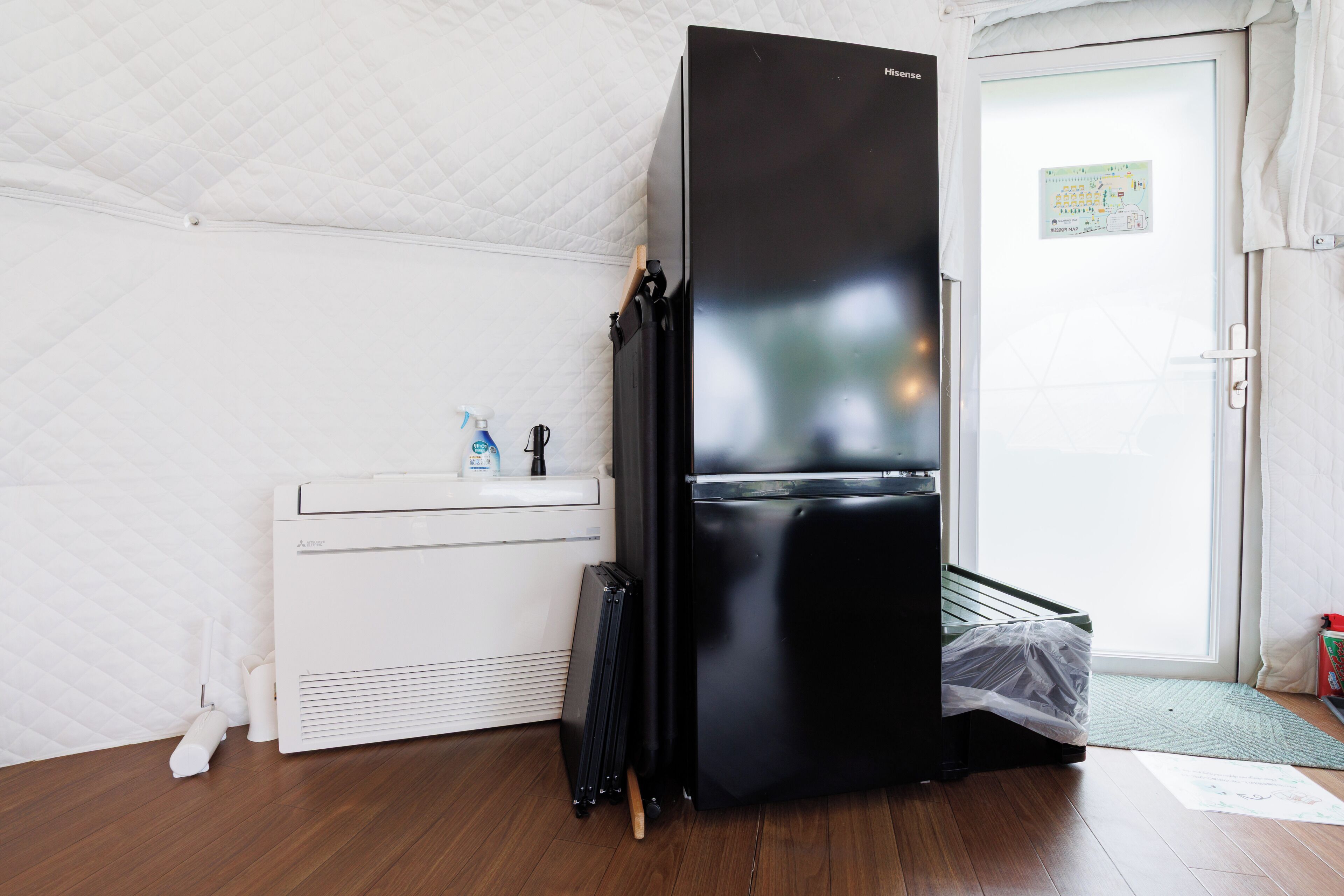 A compact room with a black refrigerator, a white washing machine, and a small sink.