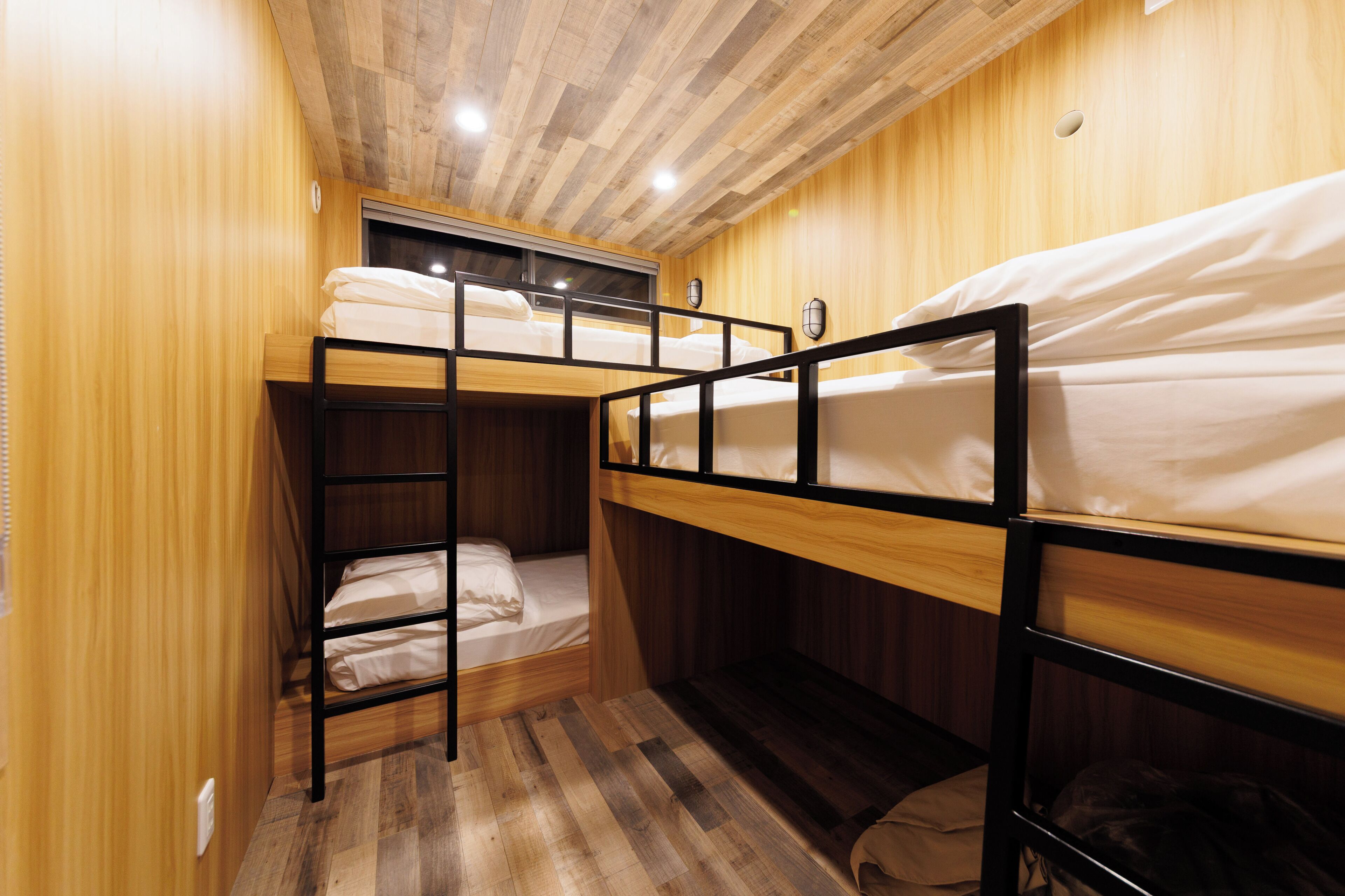 A bunk bed room with wooden walls and a sloped ceiling.