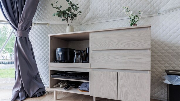 A modern kitchen with a built-in wooden cabinet, a coffee maker, and a plant on the countertop. - Gramping Stay Tomamu (Shimukappu)